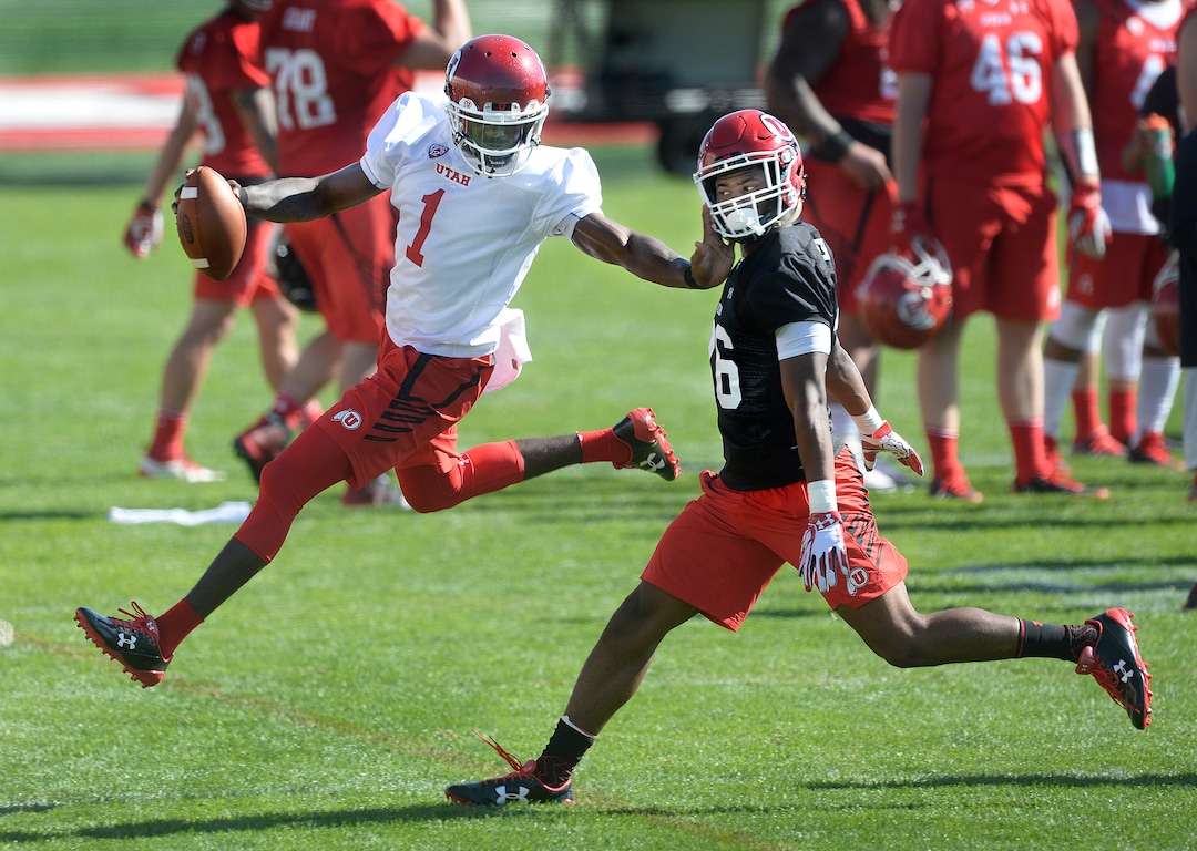 Scott Sommerdorf   |  The Salt Lake Tribune  Utah QB Tyler Huntley stiff arms DB Terrell Burgess during the first day of Utah fall football camp, Friday, July 28, 2017.  