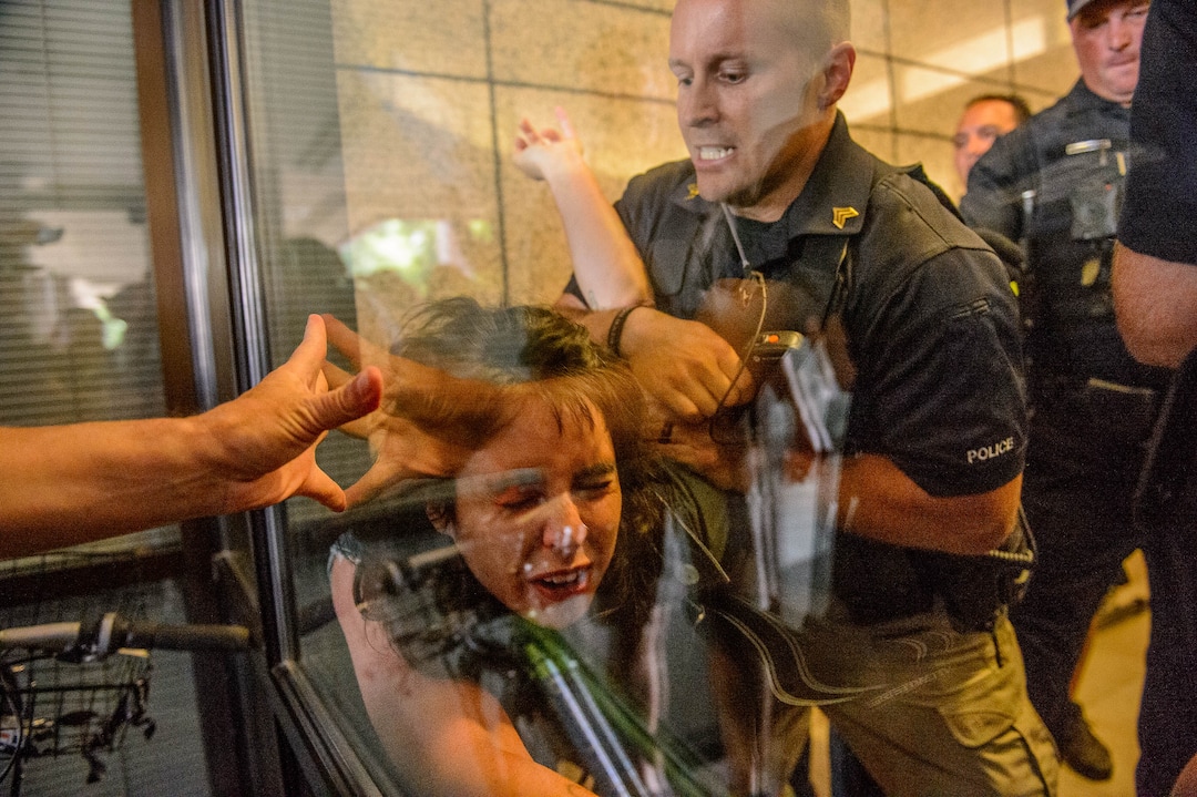 (Trent Nelson  |  The Salt Lake Tribune) Police take a woman into custody while removing protesters occupying the Chamber of Commerce Building Salt Lake City on Tuesday, July 9, 2019. Dozens of people showed up to protest the proposed Inland Port and ended up clashing with police, resulting in temporary street closures and arrests.