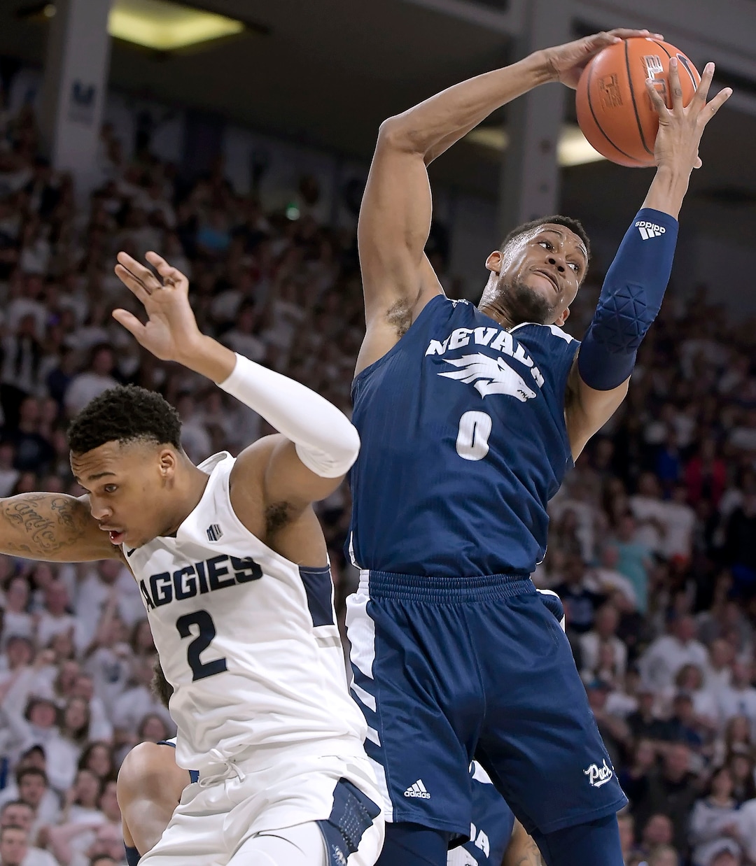 (Eli Lucero  |  The Herald Journal via AP) Nevada forward Tre'Shawn Thurman (0) grabs a rebound over Utah State forward Dwayne Brown Jr. (2) during an NCAA college basketball game, Saturday, March 2, 2019, in Logan, Utah.