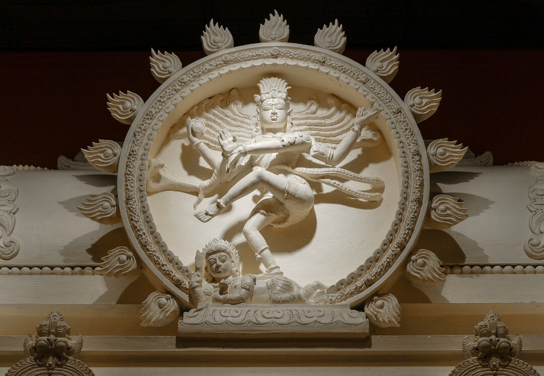 Leah Hogsten  |  The Salt Lake Tribune  Nataraja or Nataraj, the dancing form of Lord Shiva, is a symbolic synthesis of the most important aspects of Hinduism, and the summary of the central tenets of this Vedic religion. Snakes that stand for egotism, are seen uncoiling from his arms, legs, and hair, which is braided and bejeweled. His matted locks are whirling as he dances within an arch of flames representing the endless cycle of birth and death. On his head is a skull, which symbolizes his conquest over death. Goddess Ganga, the epitome of the holy river Ganges, also sits on his hairdo. His third eye is symbolic of enlightenment. The whole idol rests on a lotus pedestal, the symbol of the creative forces of the universe. Artisans from around the world spent two years hand-carving deities in the Sri Ganesha Hindu Temple in South Jordan. 