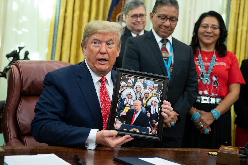 (Evan Vucci | AP) President Donald Trump shows off a gift during and event to sign an executive order establishing the Task Force on Missing and Murdered American Indians and Alaska Natives, in the Oval Office of the White House, Tuesday, Nov. 26, 2019, in Washington.