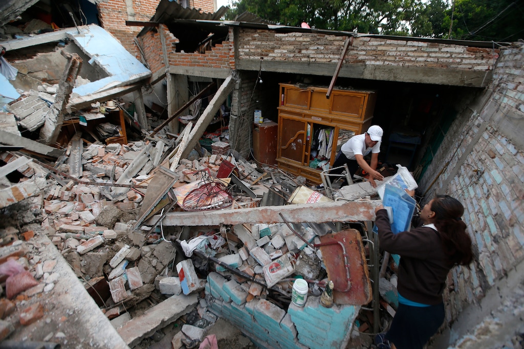 Residents salvage personal items from a home destroyed in a 7.1 earthquake, in Jojutla, Morelos state, Mexico, Wednesday, Sept. 20, 2017. Police, firefighters and ordinary Mexicans are digging frantically through the rubble of collapsed schools, homes and apartment buildings, looking for survivors of Mexico's deadliest earthquake in decades as the number of confirmed fatalities climbs. (AP Photo/Eduardo Verdugo)