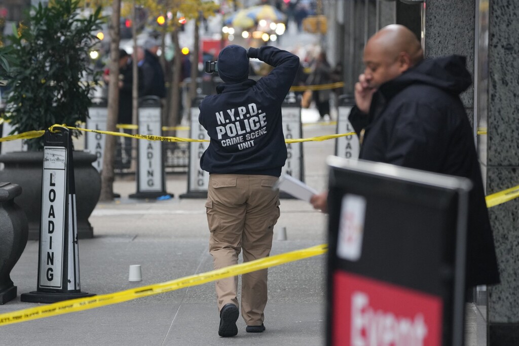 A crime scene unit officer photographs the scene where UnitedHealthcare CEO Brian Thompson, 50, was shot and killed. | Getty Images—AFP/Bryan R. Smith