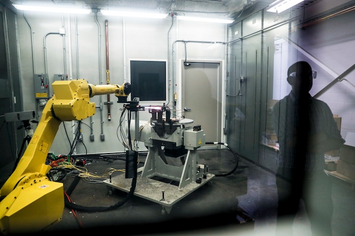 In this Thursday, May 18, 2017 photo, a robotic arm with a high-intensity blowtorch is remotely operated to test ceramic matrix composites, which make engines more durable, heat-resistant and efficient, at the General Electric Aviation plant in Evendale, Ohio. At GE Aviation, internships and co-ops with colleges attract younger prospective employees, while veteran workers are retrained. The giant Building 700 is home to white-coated scientists clustered in the FastWorks Lab nestled inside the decades old building, while much of the rest is relatively quiet. (AP Photo/John Minchillo)