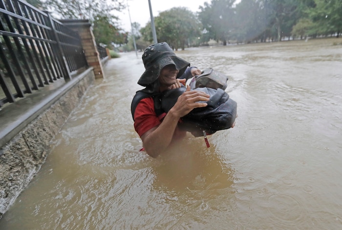 (David J. Phillip | The Associated Press) Residents wade through floodwaters from Tropical Storm Harvey Sunday, Aug. 27, 2017, in Houston, Texas.