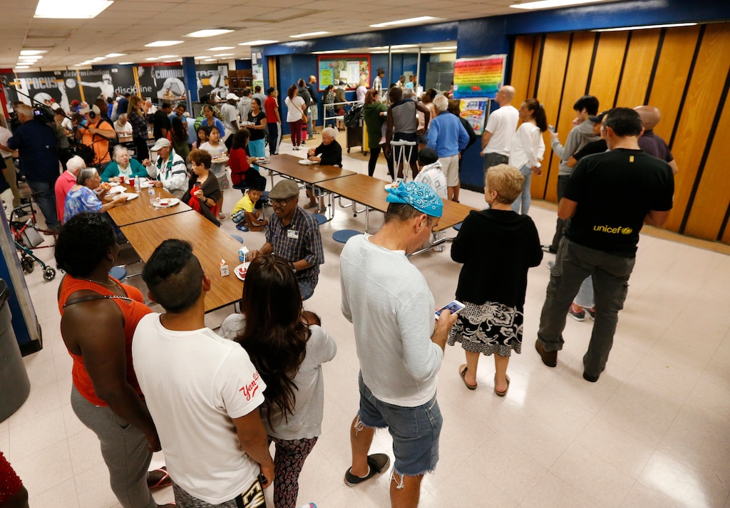 People at a Red Cross shelter set up at North Miami Beach Senior High School wait in line for lunch, Friday, Sept. 8, 2017 in North Miami Beach, Fla. Cuba evacuated tourists from beachside resorts and Floridians emptied stores of plywood and bottled water after Hurricane Irma left at least 20 people dead and thousands homeless on a devastated string of Caribbean islands and spun toward Florida for what could be a catastrophic blow this weekend. (AP Photo/Wilfredo Lee)