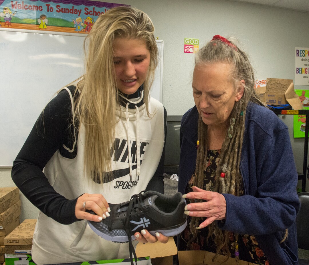 (Rick Egan  |  The Salt Lake Tribune)     Volunteer Bentley Ballard assists Mickie Hunter with a new pair of shoes, at the 25th annual Thanksgiving Dinner for the hungry and homeless at the Christian Life Center on Redwood Road in Salt Lake City, Wednesday, Nov. 21, 2018.