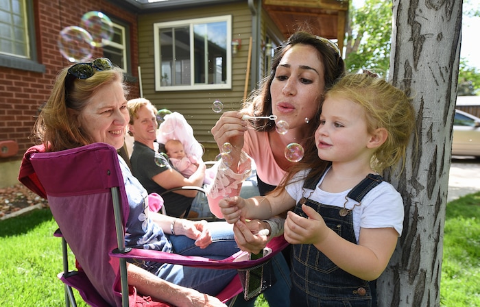 (Francisco Kjolseth | The Salt Lake Tribune) Rachel Allen blows bubbles with her daughter Audrey, 3, as her mother Jane Danowit, visiting from Wisconsin takes in the fun in the family's backyard in Salt Lake on Thursday, May 3, 2018. Scott Allen, in background with their young daughter Cora, 11-weeks, says he wants to raise his kids as free range but his toddler is "constantly trying to kill herself." His wife tends to be a little more vigilant in looking after the kids. Rachel and her husband Scott are anesthesiologists in a burn unit. As doctors, they're trying to balance a free range childhood with safety practices to prevent their kids experiencing the injuries they witness at work every day. Utah is believed to be the first state to pass a law that prevents parents from being prosecuted for allowing mature kids with good judgement to do things alone, provided they are otherwise cared for.