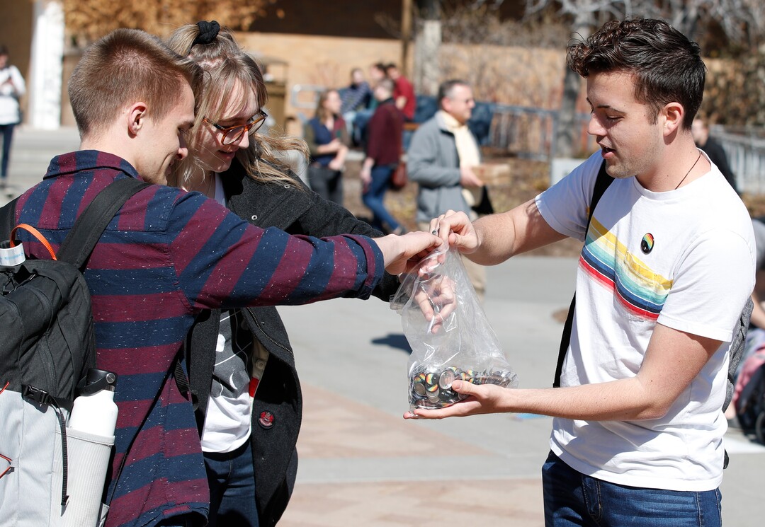 (George Frey  |  special to The Salt Lake Tribune) A BYU student holds out buttons in front of the Ernest L. Wilkinson Student Center on the campus of Brigham Young University protesting as other NYU students protest BYUÕs rollback of a newly announced policy change on LGBTQ students on March 5, 2020 in Provo, Utah.
