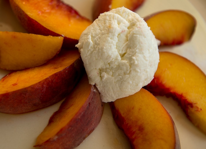 (Leah Hogsten  |  The Salt Lake Tribune) Mesa Farm owner Randy Ramsley sells a variety of goats milk cheeses and yogurt at his farm's storefront on Highway 24, east of Capitol Reef and at Tony Caputo's in Salt Lake City. Ramsley makes a variety of goats milk cheeses including pasteurized tomme, raw tomme, feta yogurt and chevre, served at right, with peaches for Ramsley's mid-morning snack. Ramsley also makes ricotta on occasion.
