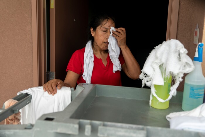 (Ilana Panich-Linsman | The New York Times) Dominga Rodriguez wipes sweat from her brow during a shift as a hotel housekeeper in Houston, July 19, 2020. Houston, one of America's fastest-warming cities, could average 109 days a year with the heat index topping 100 degrees.