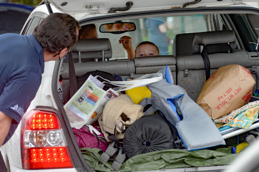 (Francisco Kjolseth  |  The Salt Lake Tribune) A young boy peeks out from the back seat as people load up the back of the car with food for the third “Miracle Project” for the nonprofit foundation which raises money to purchase food produced by Utah farmers and then gives to residents in need, takes place at the Utah State Fairpark in Salt Lake City on Monday, July 27, 2020. The food donation from the Utah Farm Bureau’s “Farmers Feeding Utah” program provided food for 600 individuals and families who have recently become unemployed due to the coronavirus.