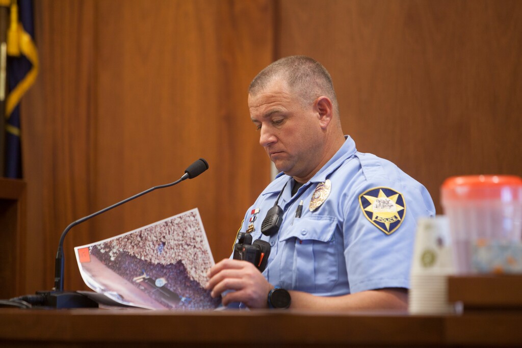 (Chris Caldwell | The Spectrum | The Associated Press) In this Monday, June 18, 2018 photo, Officer Gage Schimbeck, Pine View Middle School Resource Officer and St. George Police Bomb Squad, looks over photographs as he testifies in St. George, Utah, during a preliminary hearing for a 16-year-old boy accused of bringing a incendiary device to Pine View High School. The  Utah teenager told police that he tried to blow up a homemade device in his backpack at school because he'd been looking at Islamic State propaganda and wanted to cause fear, according to a video of the conversation shown in court Monday.