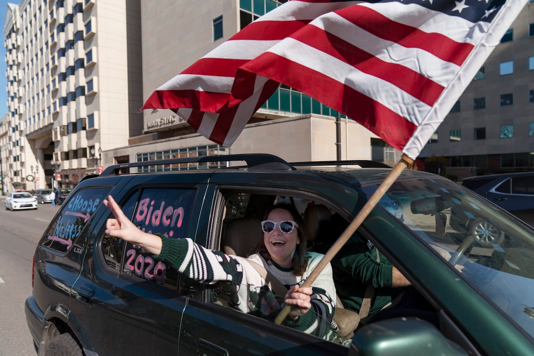 A Biden supporter cheers while driving past a Trump rally protesting the election results after Democrat Joe Biden was declared the winner Saturday, Nov. 7, 2020, at the State Capitol in Lansing, Mich. Biden defeated President Donald Trump to become the 46th president of the United States on Saturday, positioning himself to lead a nation gripped by the historic pandemic and a confluence of economic and social turmoil. (AP Photo/David Goldman)