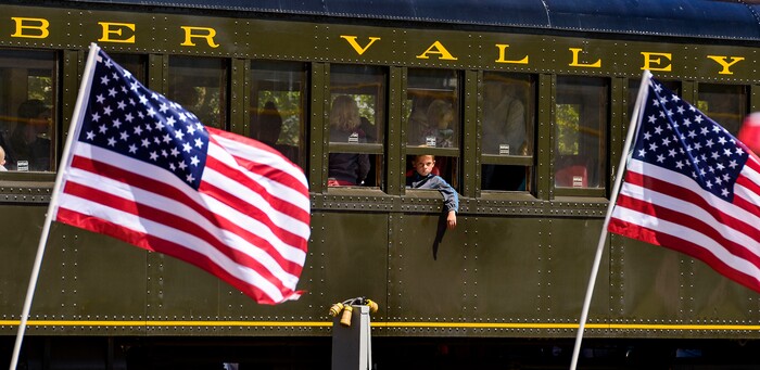 (Leah Hogsten  |  The Salt Lake Tribune) A passenger in a train car at the historic Heber Valley Railroad watches American flags waving in the wind to honor military, past and present, men and women who serve or have served in our Armed Forces in celebration of Heber City 2020 Memorial Day Drive By Tribute, May 25, 2020.