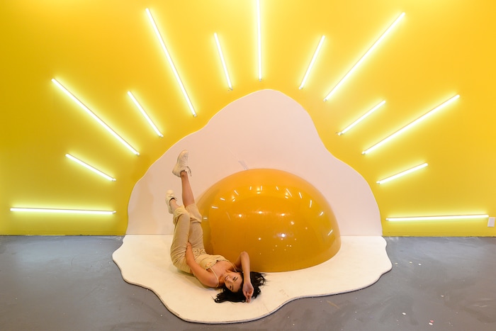 (Francisco Kjolseth  |  The Salt Lake Tribune)  Jiajing Yi poses in the egg room at Hall of Breakfast, a quirky new art exhibit that celebrates the first meal of the day. Each room celebrates a favorite breakfast food from bacon to cereal to coffee. The exhibit runs through July 9.