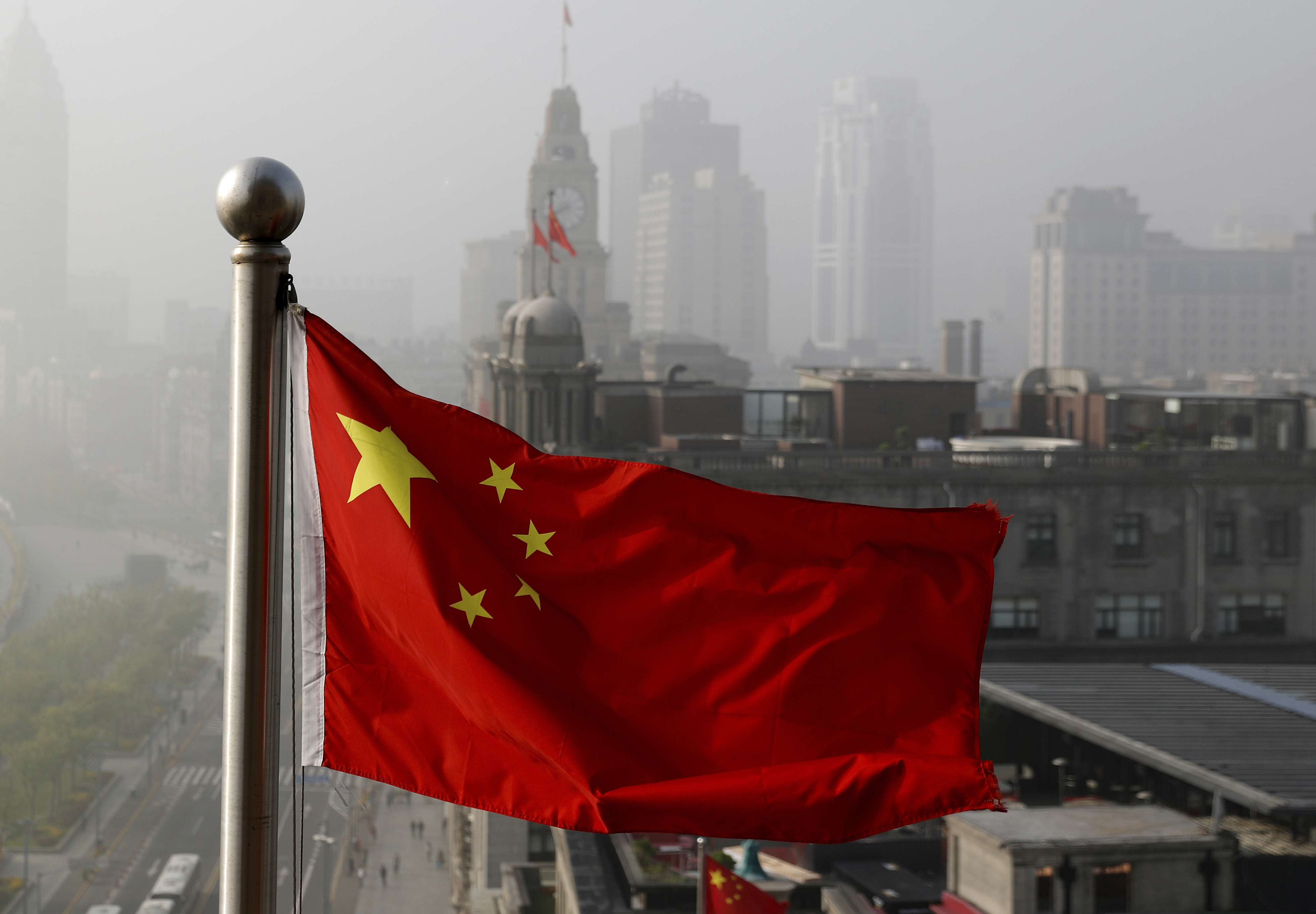 FILE - In this April 14, 2016 file photo, a Chinese national flag flutters against the office buildings in Shanghai, China.  (AP Photo/Andy Wong, File)