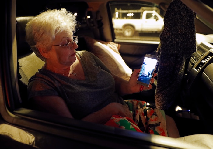 Volcano evacuee Stella Calio, a resident of Lelani Estates, watches social media videos of the volcanic eruption that took place just blocks from her home, Friday, May 4, 2018, in Pahoa, Hawaii. Calio, her husband, and two dogs are staying at a shelter a few miles from the lava eruption. (AP Photo/Marco Garcia)