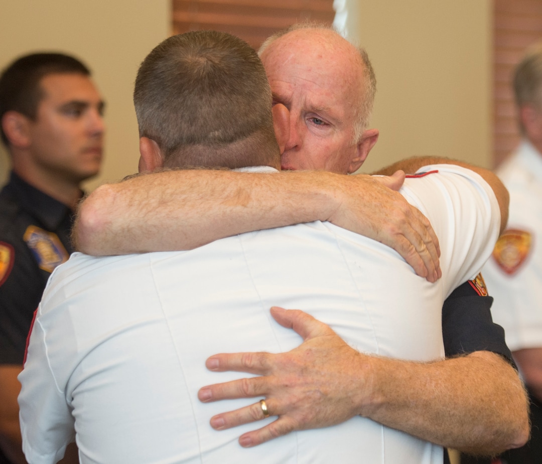 (Rick Egan  |  The Salt Lake Tribune)       Batt. Chief Duane Woolsey with Unified Fire hugs Draper Fire Battalion Chief Bart Vawdrey before a press conference at Draper City Hall about Matt Burchett, 42, who died fighting wildfires in California. Tuesday, Aug. 14, 2018.