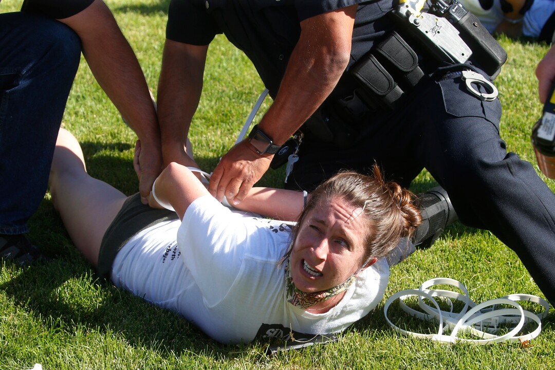 A protester is handcuffed by Cottonwood Heights police officers during a march Sunday, Aug. 2, 2020, in Cottonwood Heights, Utah. The protest was a "March for Justice" focused largely around Zane James, who was fatally shot by police in Cottonwood Heights in 2018. (AP Photo/Rick Bowmer)