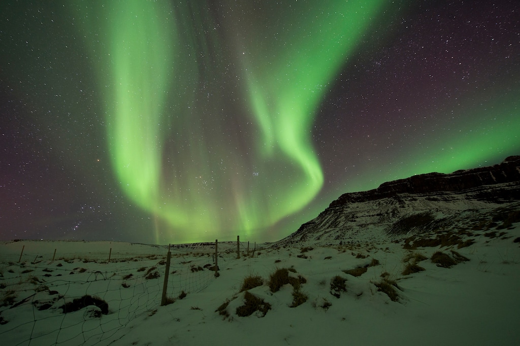 FILE - In this March 1, 2017 file photo, the Northern Lights, or aurora borealis, appear in the sky over Bifrost, Western Iceland. Police in Iceland say tourists are often putting themselves at risk searching for the Northern Lights, whose spectacular streaks of color light up the winter skies at night. Police say sleep-deprived tourists are dividing their attentions between the road and the sky, and often underestimate the challenging conditions posed by Iceland’s twisty, narrow, often-icy roads in the winter. (AP Photo/Rene Rossignaud, File)