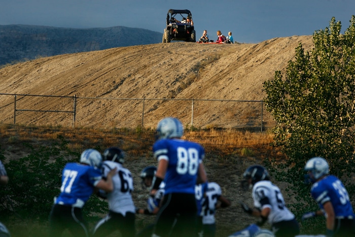 (Scott Sommerdorf   |  The Salt Lake Tribune) Duchesne and Carbon play as a family watches from a hilltop near the Carbon High football field. The Eagles would go on to an easy 35-0 win against Carbon High which ran their winning streak to 37 games, setting the Utah state record for consecutive wins, Friday, September 6, 2013. 