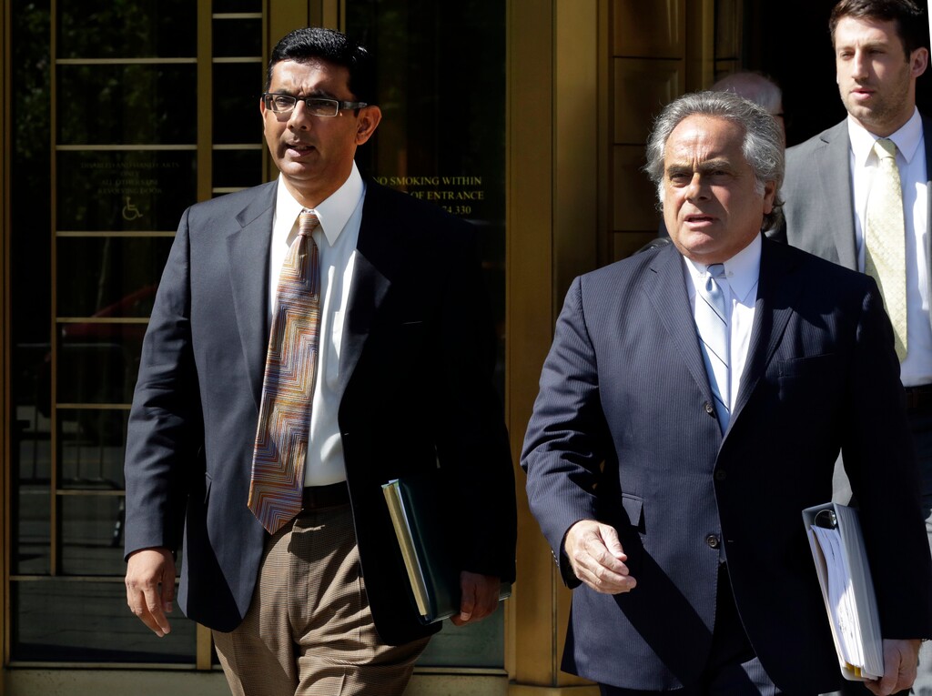 (Richard Drew | The Associated Press) In this May 20, 2014 file photo, conservative scholar and filmmaker Dinesh D'Souza, left, accompanied by his lawyer Benjamin Brafman leaves federal court, in New York. President Donald Trump says he will pardon conservative commentator Dinesh D'Souza who pleaded guilty to campaign finance fraud. Trump tweeted Thursday: “Will be giving a Full Pardon to Dinesh D’Souza today. He was treated very unfairly by our government!” D’Souza was sentenced in 2014 to five years’ probation after he pleaded guilty to violating federal election law.