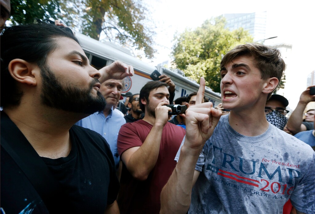 A man wearing a T-shirt bearing the name of President Donald Trump, right, argues with a counterprotester after being hit by a flying plastic bottle of water near a "Free Speech" rally staged by conservative activists, Saturday, Aug. 19, 2017, in Boston.  An estimated 15,000 counterprotesters marched through the city to historic Boston Common, where many gathered near a bandstand abandoned early by conservatives who had planned to deliver a series of speeches. Police vans later escorted the conservatives out of the area, and angry counterprotesters scuffled with armed officers trying to maintain order.  (AP Photo/Michael Dwyer)