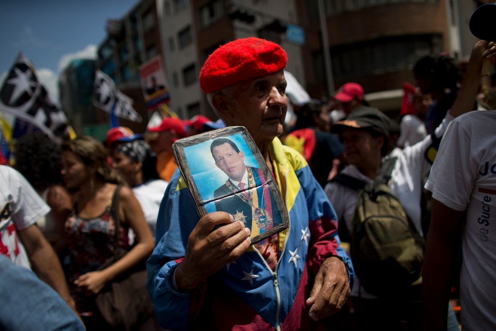(Ariana Cubillos | Associated Press file photo) A supporter of Venezuela's President Nicolas Maduro holds a picture of the late President Hugo Chavez during an anti-imperialist march in Caracas, Venezuela, on March 16, 2019. Many were clad in red, the color associated with the movement led by Chavez, the former military officer who declared a socialist "revolution" after coming to power in 1999.