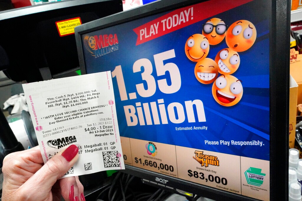 (Gene J. Puskar | AP) A customer at the Cranberry Super Mini Mart in Cranberry, Pa., shows her Mega Millions ticket on Thursday, Jan. 12, 2023.