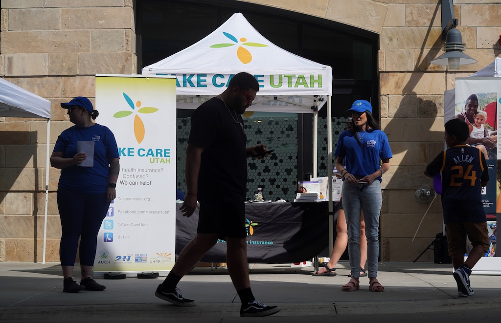 (Bethany Baker | The Salt Lake Tribune) People walk past the Take Care Utah booth, a Utah Health Policy Project program that helps Utahns access and naviagate the health care system, at the Latinx/Hispanic Health and Heritage Festival in downtown Salt Lake City on Saturday, Sept. 9, 2023.