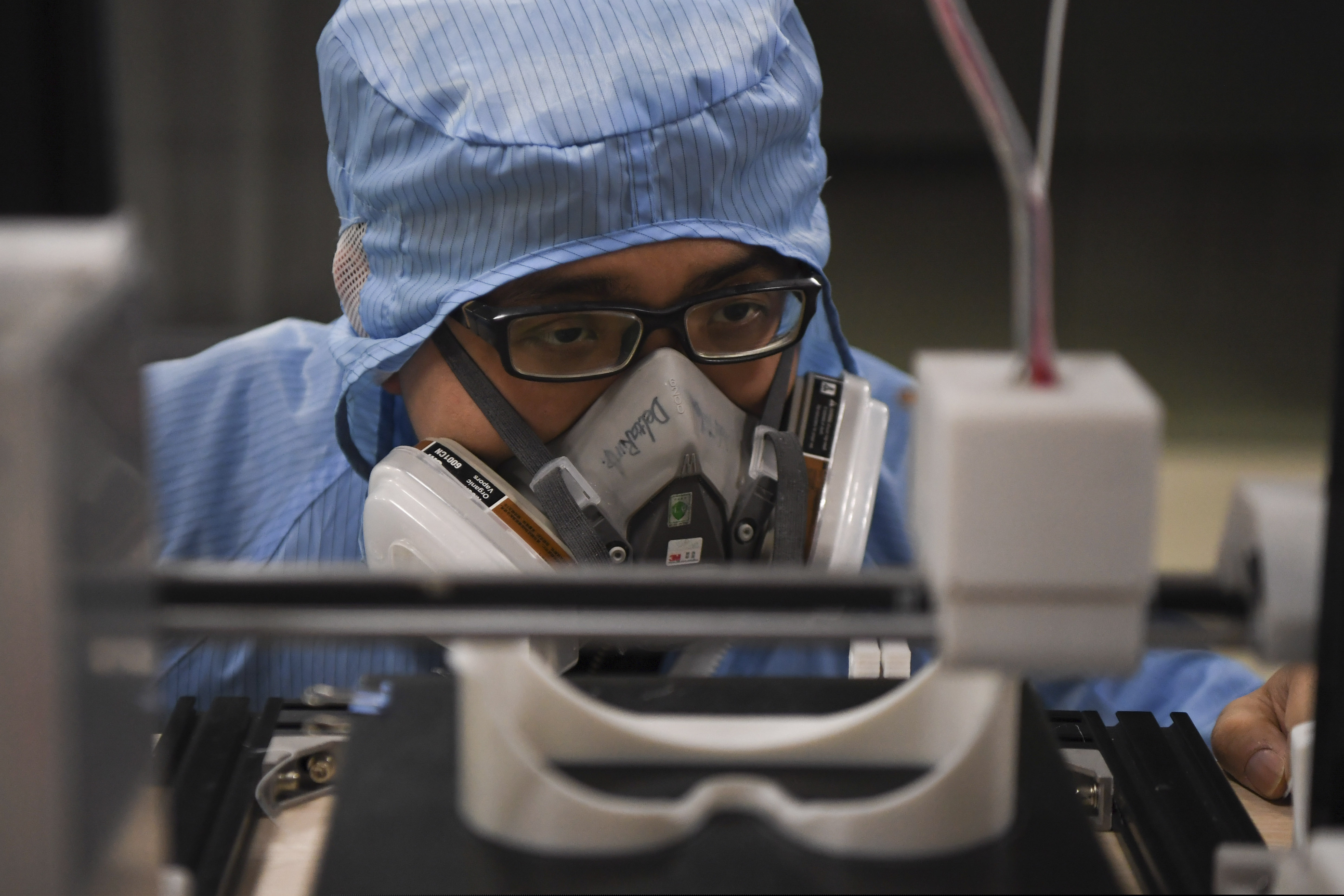 In this photo released by Xinhua News Agency, a worker inspects the operation of a 3D printer at the additive manufacturing research and application center of the Hunan Vanguard Group Co., Ltd. in the economic development zone of Changsha city in central China's Hunan Province, on Tuesday, Feb. 11, 2020. The company has been producing goggles for medical use with more than 50 3D printers working day and night for use in hospital fighting the novel coronavirus outbreak. (Xue Yuge/Xinhua via AP)