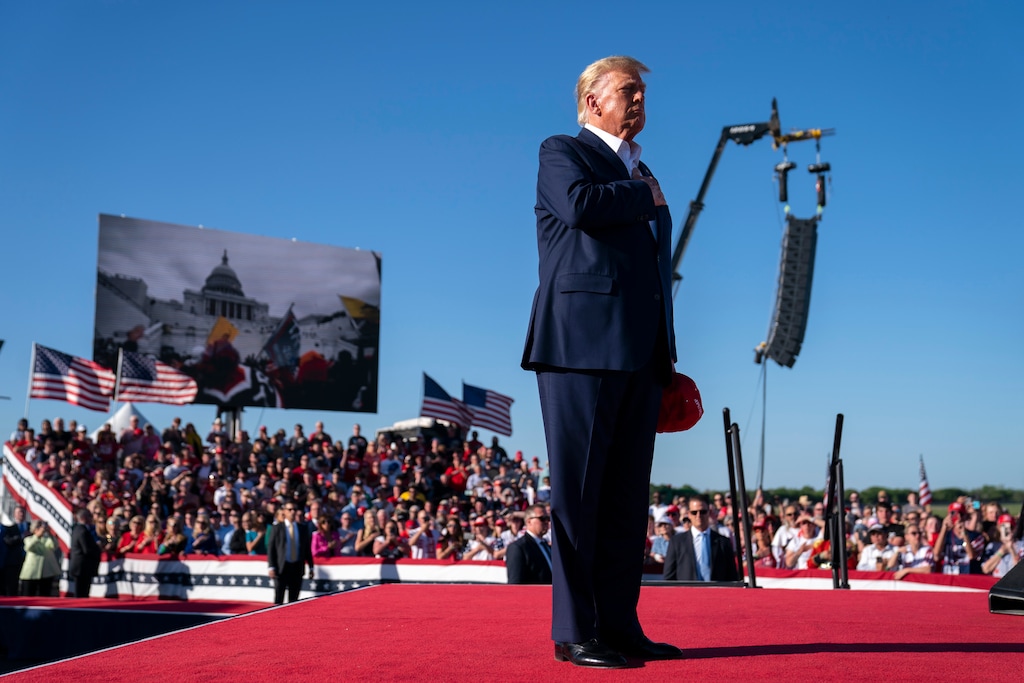 (Evan Vucci | AP) As footage from the Jan. 6, 2021, insurrection at the U.S. Capitol is displayed in the background, former President Donald Trump stands while a song, "Justice for All," is played during a campaign rally March 25, 2023, in Waco, Texas. Salt Lake Tribune columnist Gordon Monson says the LDS Church's warning against straight-ticket voting can be viewed as advice for members to weigh whether to vote for Trump in 2024.