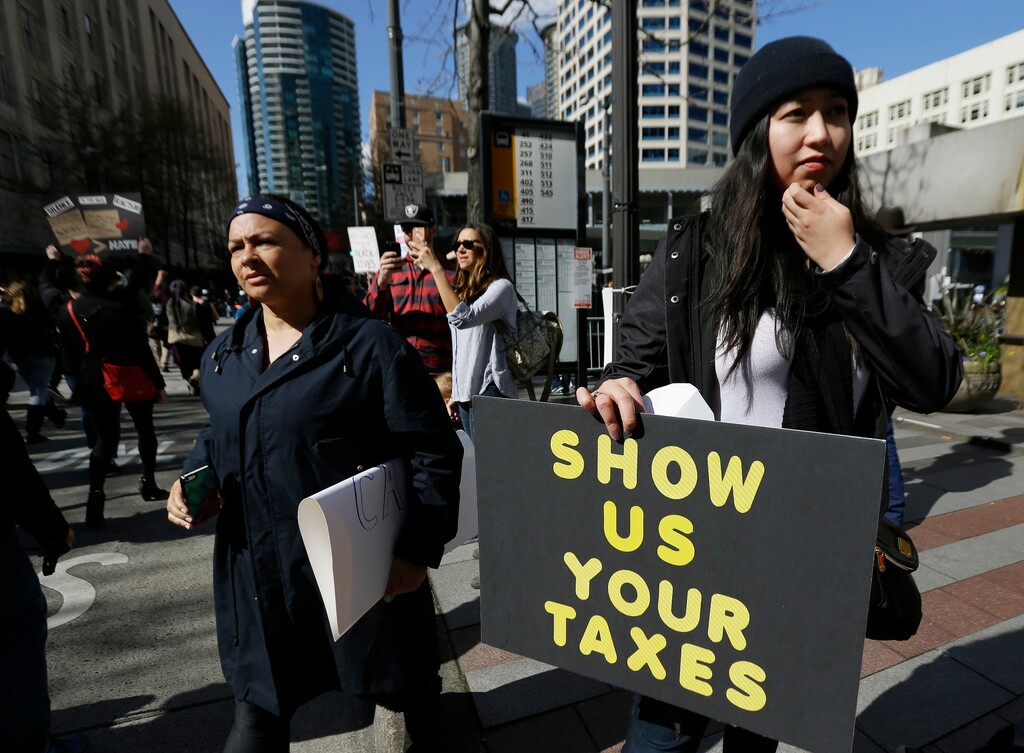 A woman in Seattle holds a sign during a rally that reads "Show us your taxes" in reference to calls for President Donald Trump to release his tax returns, so Americans can scrutinize his business ties and potential conflicts of interest, Saturday, April 15, 2017. Trump was the first major-party nominee in more than 40 years not to release his tax returns, saying it was because he was under audit. Similar rallies were held in other U.S. cities as the deadline approaches for 2016 tax returns to be filed. (AP Photo/Ted S. Warren)