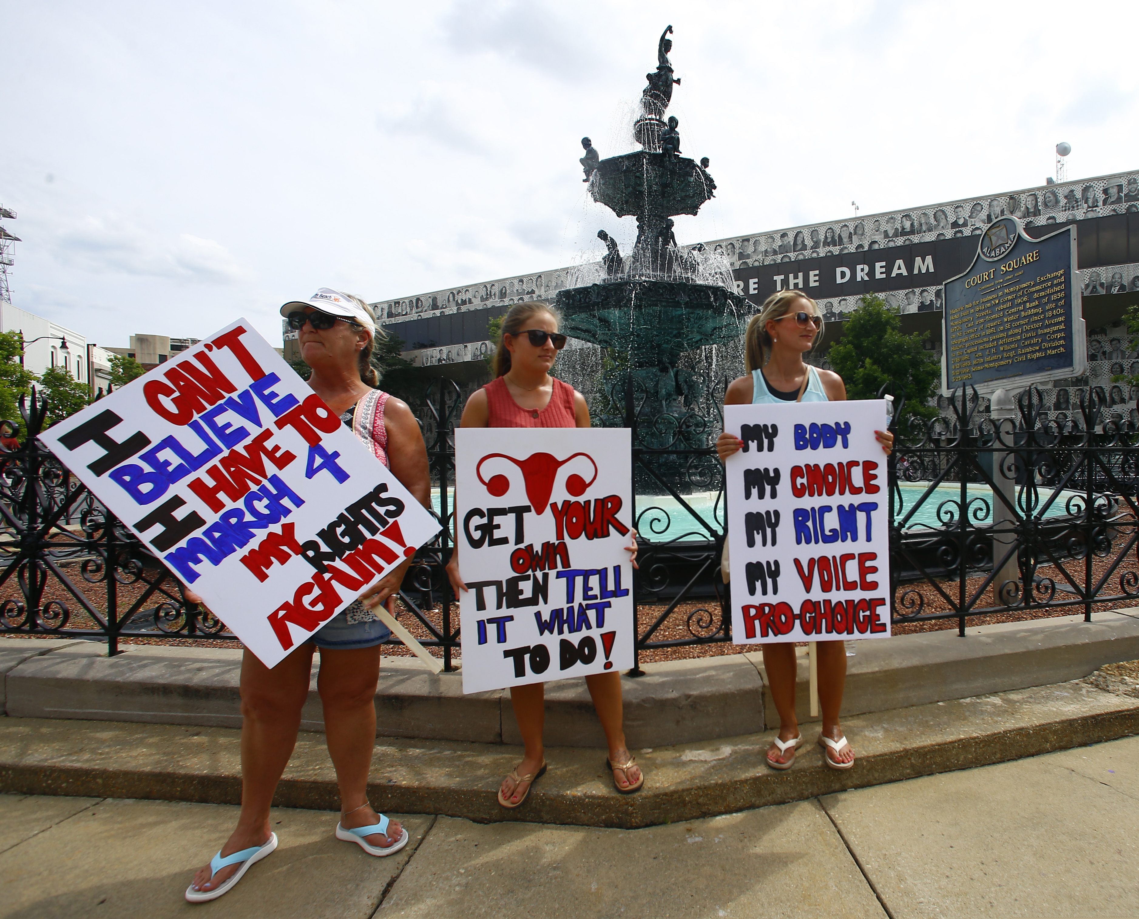 (Butch Dill | AP) Women hold signs as they gather to march to the Capitol for women's rights, Sunday, May 19, 2019, in Montgomery, Ala.