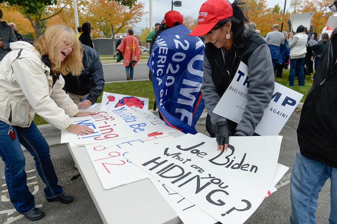 (Francisco Kjolseth | The Salt Lake Tribune) Carolyn Howard, left, and Sylvia Miera-Fisk laugh as they overlook their signage as two competing rallies spar near Rep. Ben McAdams' office in West Jordan, one seeking to support McAdams and one to criticize him for supporting the impeachment inquiry of President Donald Trump on Wednesday, Oct. 9, 2019.