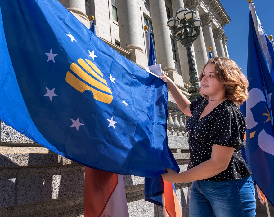 (Leah Hogsten | The Salt Lake Tribune)  State flag designer finalist  Angelina Nading of Vernal poses with her design after a press conference that revealed the 20 semifinal designs for the creation of the new state flag, Sept. 22, 2022 at the Utah Capitol. On Thursday, the Utah Department of Cultural & Community Engagement unfurled the 20 semifinal designs, now on display in the Hall of Governors. The design review committee is seeking public feedback through a SurveyMonkey form until Oct. 5, 2022. After that time, four to six flags will be presented to the task force, led by Gov. Spencer Cox and Lt. Gov. Deidre Henderson. The final design will be presented to the Legislature later this fall.
