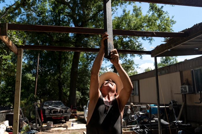 (Ilana Panich-Linsman | The New York Times) Candelario Rodriguez, an out-of-work roofer, helps a neighbor build a carport in Houston, July 23, 2020. Around the world, the poor and marginalized are much more likely to be vulnerable to extreme heat; three of Candelario's co-workers have collapsed from heat exhaustion over the years.