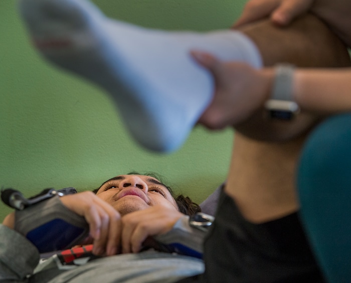 (Leah Hogsten  |  The Salt Lake Tribune) Stak gets encouragement from his physical therapist who tells him that his leg muscles “are firing” as she stretches and manipulates his legs prior to their workout. Audrick “Stak” Afatasi is fighting to regain movement in his lower body after being paralyzed at a trampoline park on March 15, 2019.