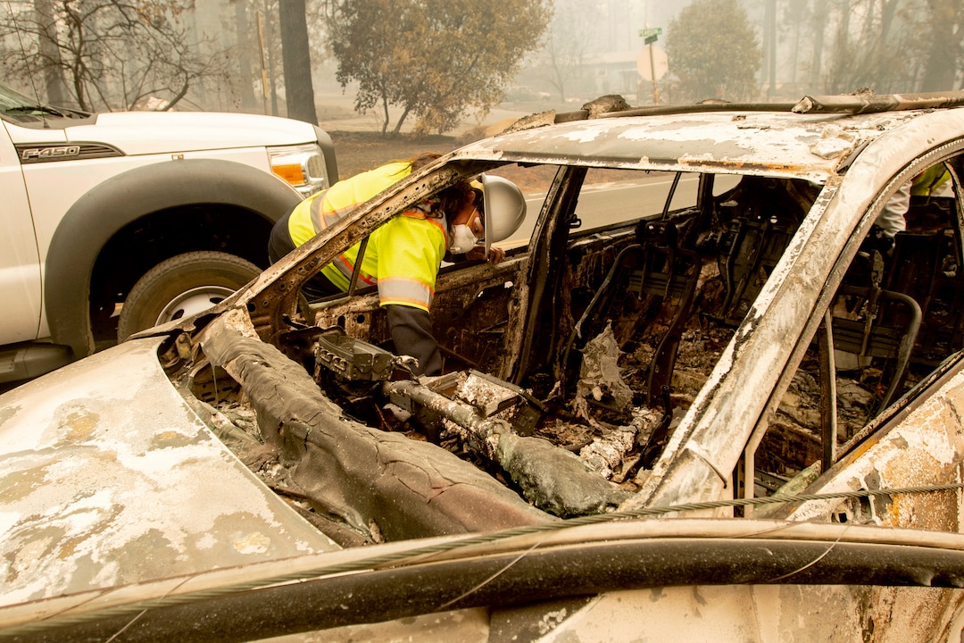 Arbana Low Dog searches through a vehicle on Pearson Rd. after the wildfire burned through Paradise, Calif., on Saturday, Nov. 10, 2018. Not much is left in Paradise after a ferocious wildfire roared through the Northern California town as residents fled and entire neighborhoods are leveled. (AP Photo/Noah Berger)