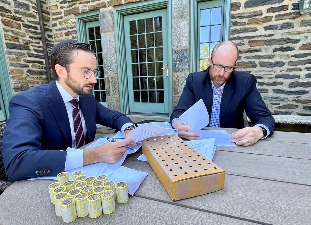 (Nathan Oman) Rabbi Itamar Rosensweig, left, and Latter-day Saint contract lawyer Nathan Oman review an agreement to sign over to Oman the title to Jewish families' leavened goods during Passover. Oman paid for these items using the silver dollars pictured and gifted to him by the rabbi.