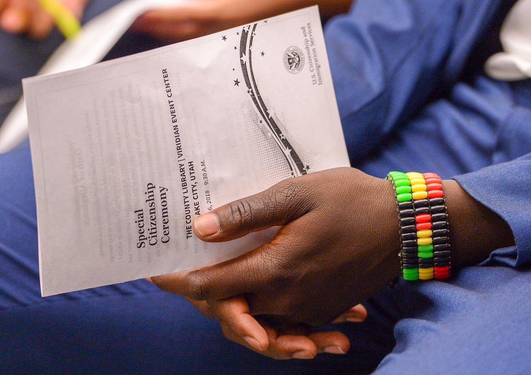 Leah Hogsten  |  The Salt Lake Tribune  Andrew Charles of Uganda sports a Kenyan bracelet during his youth naturalization ceremony at the Viridian Event Center in West Jordan, Monday, August 6, 2018. With hands on their heart 21 participants, ages 5 to 22, representing 8 countries, spoke the oath of citizenship as America's newest citizens.