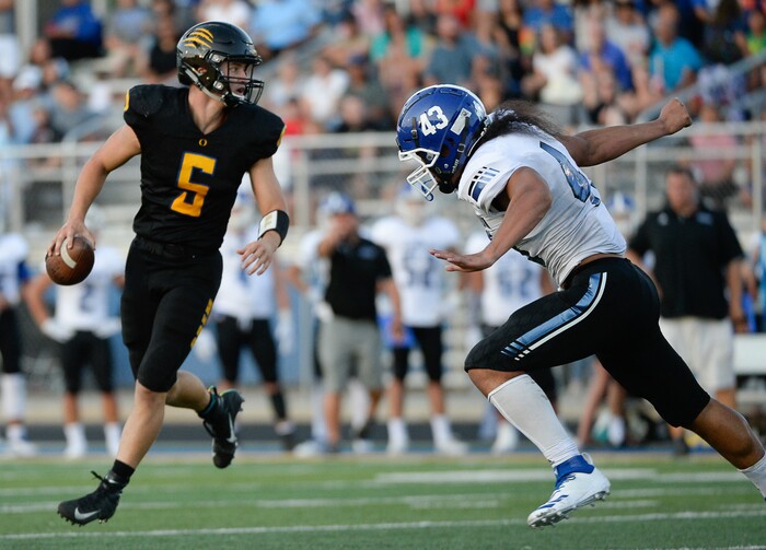 (Francisco Kjolseth  |  The Salt Lake Tribune)  Orem quarter back Cooper Legas is pressured by Orem's Lolani Langi for the start of the football season in Orem on Thursday, Aug. 16, 2018.