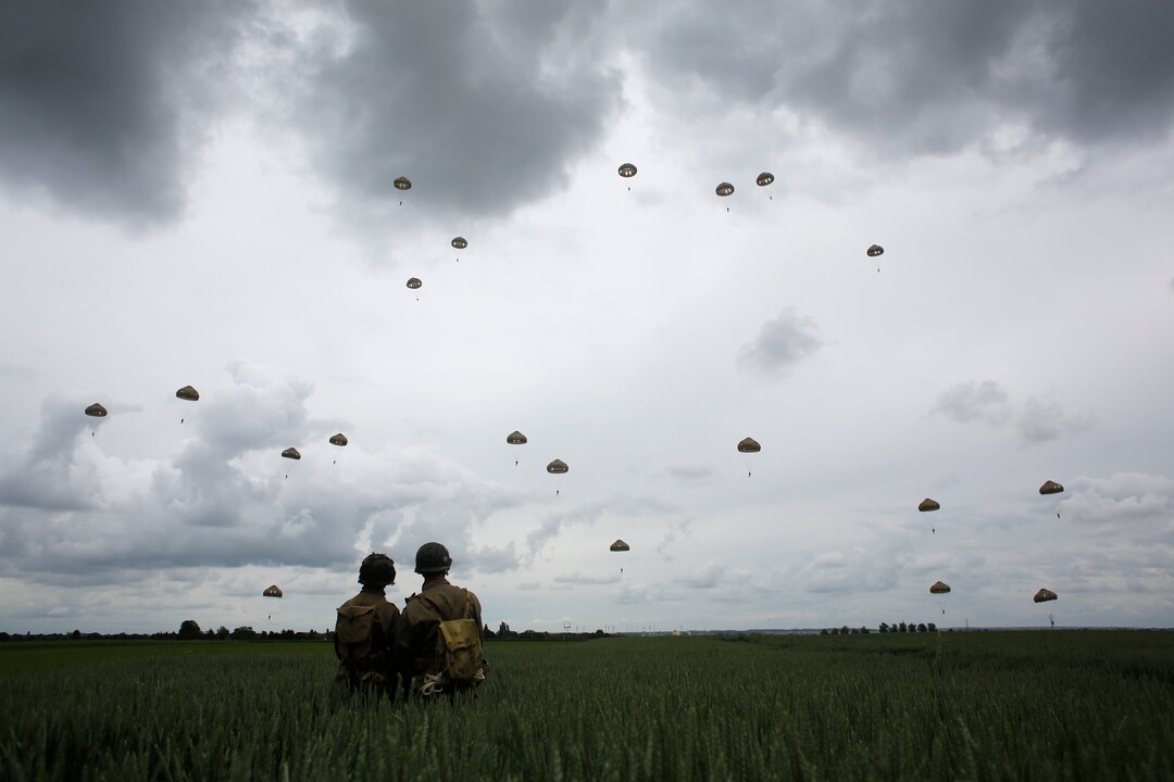 (Thibault Camus | AP) WWII enthusiasts watch French and British parachutists jumping during a commemorative parachute jump over Sannerville, Normandy, Wednesday, June 5, 2019. Extensive commemorations are being held in the U.K. and France to honor the nearly 160,000 troops from Britain, the United States, Canada and other nations who landed in Normandy on June 6, 1944 in history's biggest amphibious invasion.