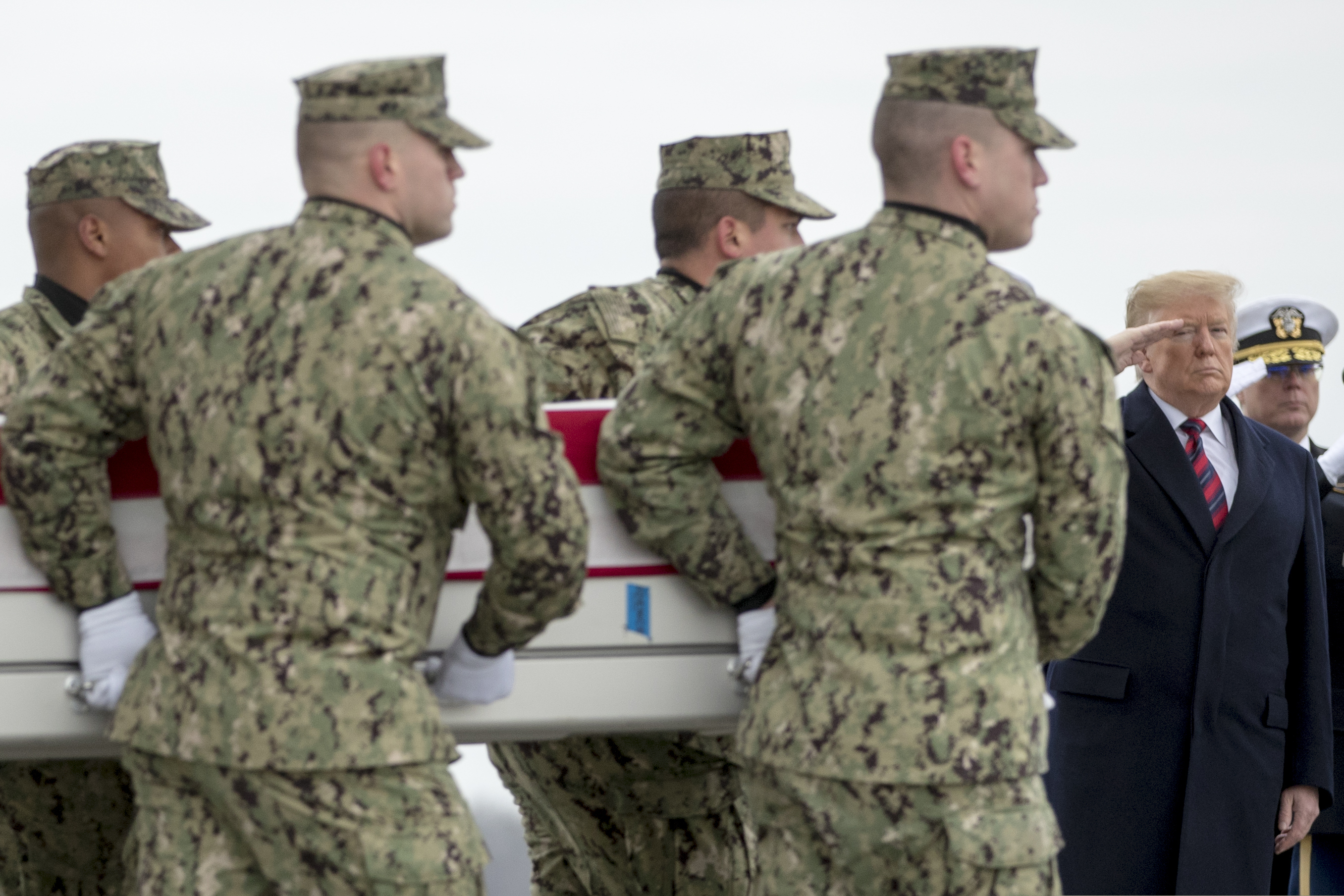 President Donald Trump salutes as a U.S. Navy carry team moves a transfer case containing the remains of Scott A. Wirtz, Saturday, Jan. 19, 2019, at Dover Air Force Base, Del. According to the Department of Defense, Wirtz, a civilian and former Navy SEAL from St. Louis, Mo., was killed Jan. 16, 2019, in a suicide bomb attack in Manbij, Syria. (AP Photo/Andrew Harnik)