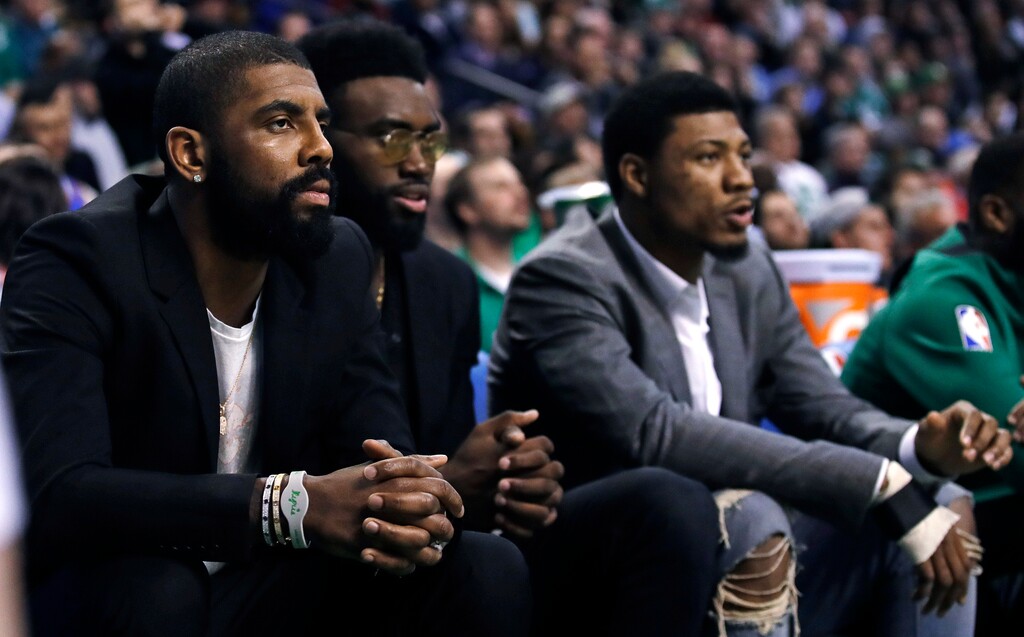 Boston Celtics guard Kyrie Irving, left, sit with teammates Jaylen Brown, center, and Marcus Smart during the first quarter of the team's NBA basketball game against the Oklahoma City Thunder in Boston, Tuesday, March 20, 2018. All three starters are sidelined with injuries. (AP Photo/Charles Krupa)