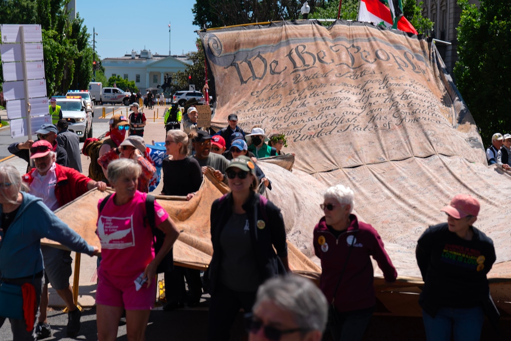 Demonstrators carry a signed banner representing the U.S. Constitution as they march near the White House during a May Day protest Friday, May 1, 2026, in Washington. (AP Photo/Jose Luis Magana)