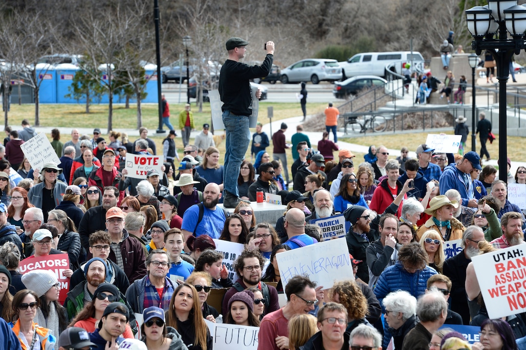 Scott Sommerdorf | The Salt Lake TribuneA man climbed op on a concrete abutment to photograph the huge crowd on the south lawn of the Utah State Capitol for the "For Our lives" rally, Saturday, March 24, 2018.