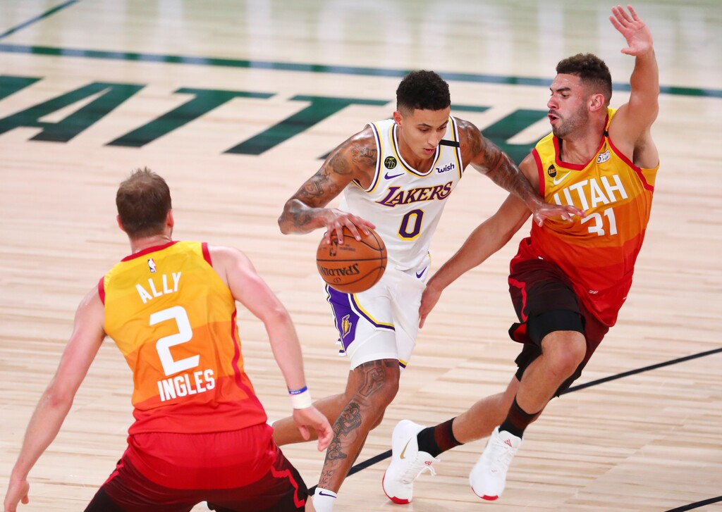 Los Angeles Lakers forward Kyle Kuzma (0) dribbles between Utah Jazz guard Joe Ingles (2) and forward Georges Niang (31) during the first half of an NBA basketball game Monday, Aug. 3, 2020, in Lake Buena Vista, Fla. (Kim Klement/Pool Photo via AP)