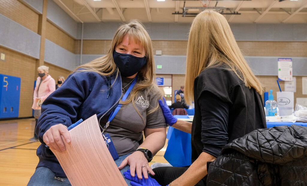 (Leah Hogsten | The Salt Lake Tribune) Michelle Sheddon, left, a reaing specialist with Ascent Academy Charter School shares a laugh with nurse Angie Boren after receiving her vaccination. Employees of the Jordan School District were invited to West Hills Middle School to receive their coronavirus vaccination, Feb. 12, 2021.